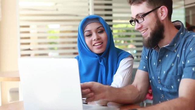 international multicultural team at work: asian muslim woman and caucasian man