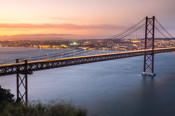 Obraz premium Sunset over the '25 of April' Bridge in Lisbon, Portugal.