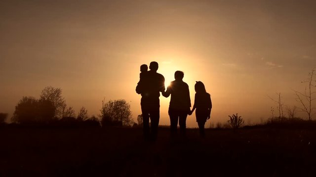 Silhouettes of grandparents with kids at sunset