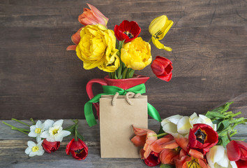 holiday concept/bouquet of multicolored tulips, paper packet on wooden background