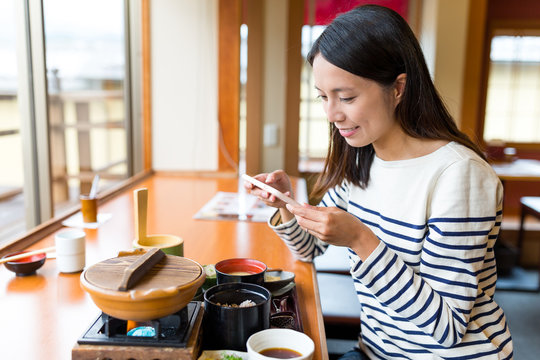 Woman taking photo on her meal in japanese restaurant