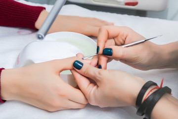 A girl has a manicure in a beauty salon, cleaning the cuticle