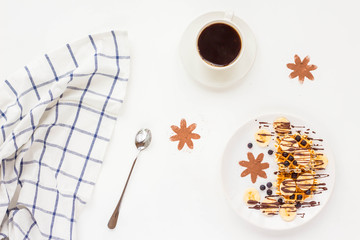 Breakfast with pate of belgian waffles with fresh fruit, chocolate, banana, berry, blueberries, cup of black coffee on white background. Flat lay, top view, mock up
