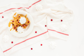 Naklejka premium Plate of belgian waffles with caramel, meringue and berry on white background. Flat lay, top view
