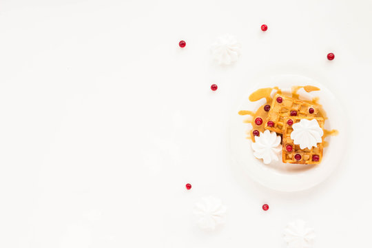 Plate of belgian waffles with caramel, meringue and berry on white background. Flat lay, top view