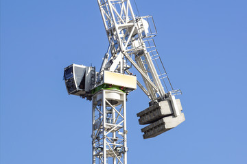 Fototapeta premium Tall white tower crane detail against bright blue sky.