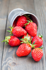 Bucket full of strawberries lying on a wooden background, vertical