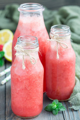 Homemade blended lemonade with fresh strawberry, lemon, ice and mint in glass bottle, vertical