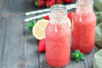 Homemade blended lemonade with fresh strawberry, lemon, ice and mint in glass bottle, horizontal, copy space