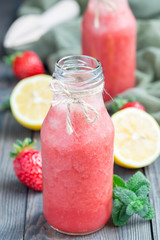 Homemade blended lemonade with fresh strawberry, lemon, ice and mint in glass bottle, vertical