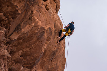 Rock climber belaying down hoodoo