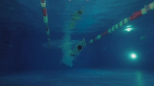 Underwater view to the beautiful professional swimmer diving into the pool and swimming crowl stroke.
