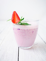 Blueberry smoothie with strawberry on white wood background. Fresh milkshake