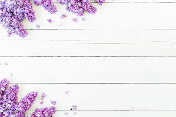 Floral pattern of lilac branches and petals on white wooden background. Flat lay, top view. Floral purple frame