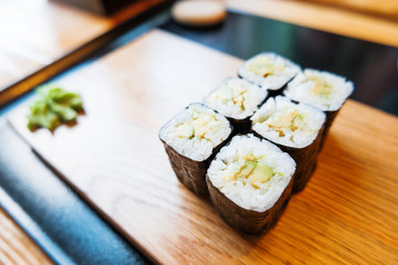 Rolls in nori seaweed with avocado, pickled ginger and soy sauce. Asian cuisine, traditional dish - sushi.
