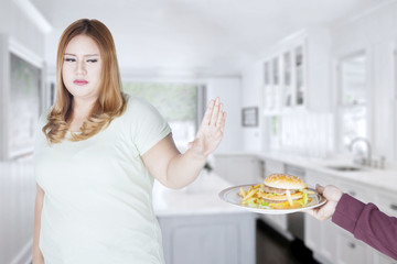 Obraz na płótnie Canvas Fat woman refusing to eat hamburger