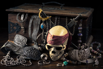 still life photography : pirate skull with two swords and treasure coffer of silver jewelry,...