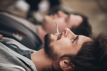 Two friends lying on the ground and smoke grass