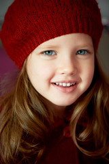 Baby 3 years old with blue eyes and white teeth in a red beret.Hair long
