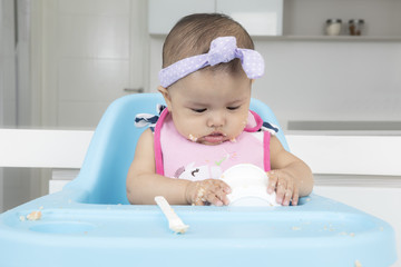 Funny baby eating food in kitchen