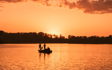 Naklejka na ściany i meble People are boating and fishing under sunset