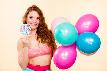 Woman holds lollipop candy and balloons