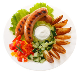 Sausages grilled with vegetables and sauce on the plate. Isolated on white background. The view...
