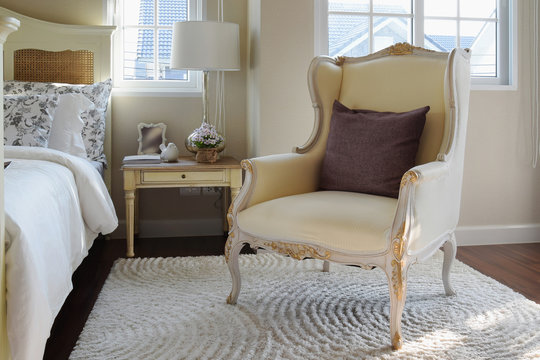 classic chair with brown pillow on carpet in vintage style bedroom interior