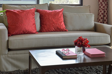 comfortable sofa with red pillows and red book on wooden table in living area at home