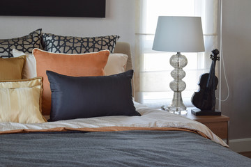 modern bedroom interior with orange and gold pillows on bed and bedside table lamp