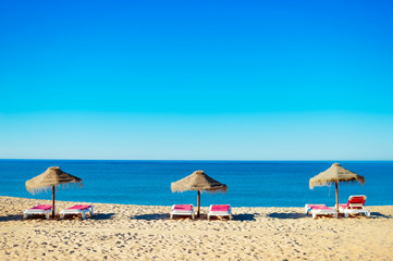 Beach umbrellas and couches on outdoors blue sky background