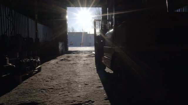 Empty Diesel Forklift Truck leaves the warehouse. Another forklift with a huge part comes into the warehouse. Working in the warehouse in winter.