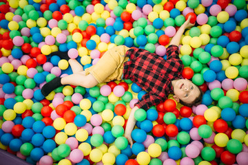 Fototapeta na wymiar Little boy lying in a pile of colorful balloons