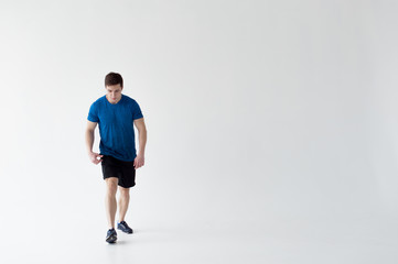 Fototapeta na wymiar Running man on low start. Stands in rack, ready to achieve goals and wins. Young sexy Muscular male athlete wearing sporty blue t-shirt and shorts, studio portrait white background.Motivation concept