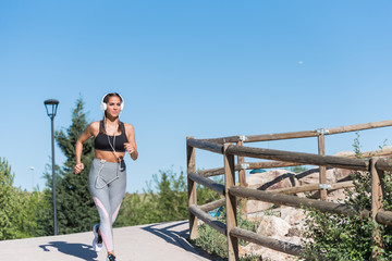 beautiful young sports Woman running jogging in a park outdoors listening music