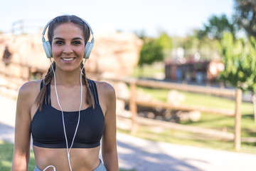 close up portrait of a woman doing sport resting outdoor smiling and listening music .