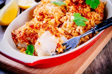 Baked codfish in breadcrumbs in gratin dish closeup