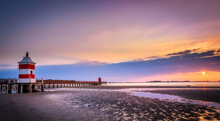 Beautiful sunrise at the seaside in Italy, at Lignano Sabbiadoro, with pier and lighthouse in the...