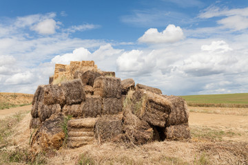 Haystack on a farm field with a blue sky and clouds