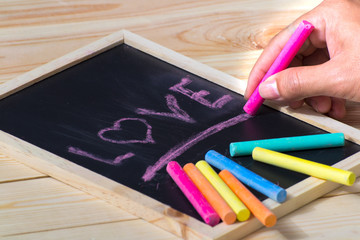 Obraz premium A colorful pastel crayons, a white paper and a hand writing an inscription 