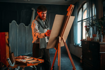 Male painter with brush in front of easel