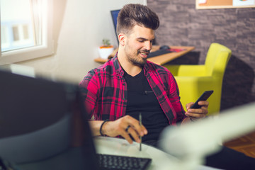 Young man using smart phone in office