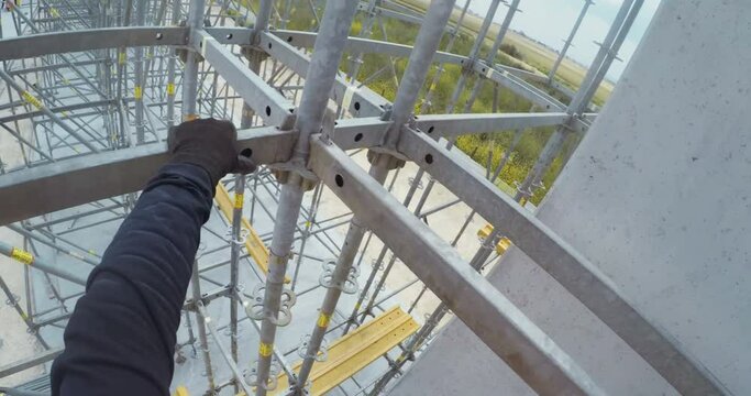 POV shot from a helmet mounted camera on a construction worker building scaffolding on a construction site