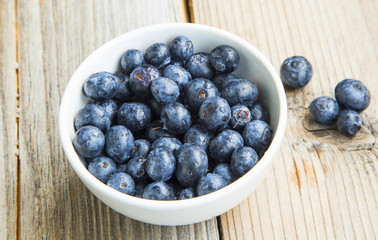 Blueberries in a bowl, healthy berry fruits in white bowl on wooden background