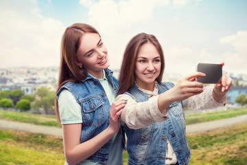 Girlfriends makes selfie, cityscape on background