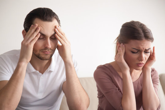 Stressed frustrated couple touching head with eyes closed, feeling strong headache or tired of arguing, exhausted man and woman trying to concentrate, lack of sleep result, hangover effect, bad day