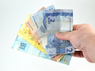 Hand holding Brazilian currency bills (real and reais) isolated, white background