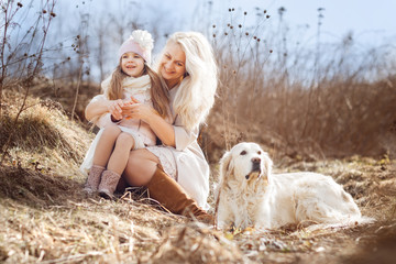 Mom and daughter with big dog outdoor. Spring, gold retriever.