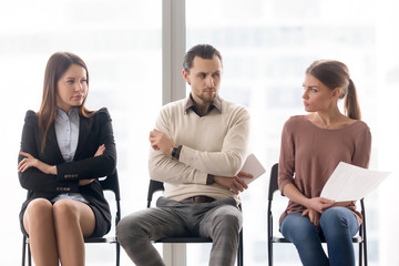 Male and female candidates waiting for interview, sitting together in a row, looking at each other...
