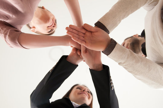 Businesspeople put hands on top of each other as symbol of team building, partnership, business ventures, firm intention to achieve success, working project, teamwork or unity concept, view from below